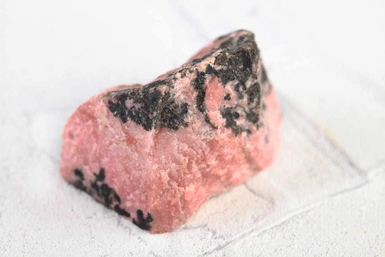 Rhodonite : Origines, propriétés et vertus 2 Pierre brute de rhodonite posee